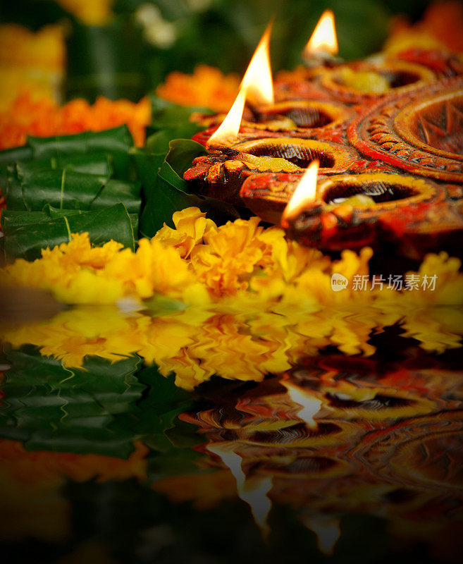 印度排灯节庆祝活动的垂直图片，通过照明彩色的Diya灯灯与金盏花和绿叶的loral rangoli